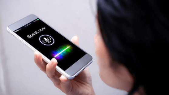 A person speaking to a voice assistant on a phone showing a microphone and a glowing sound wave